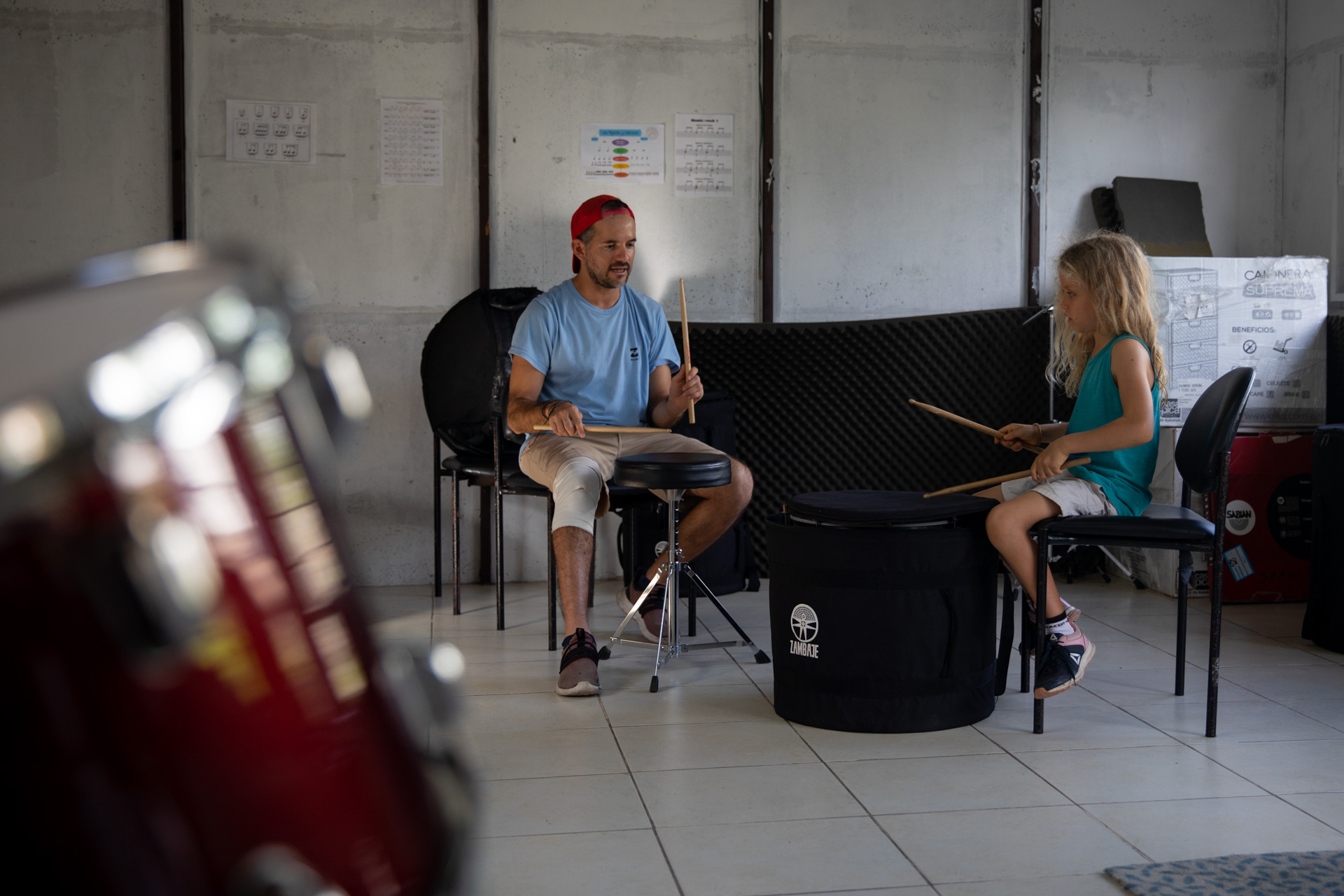 Gonzalo Fernandez and a young girl both are holding drumsticks and playing the drums during one of his classes