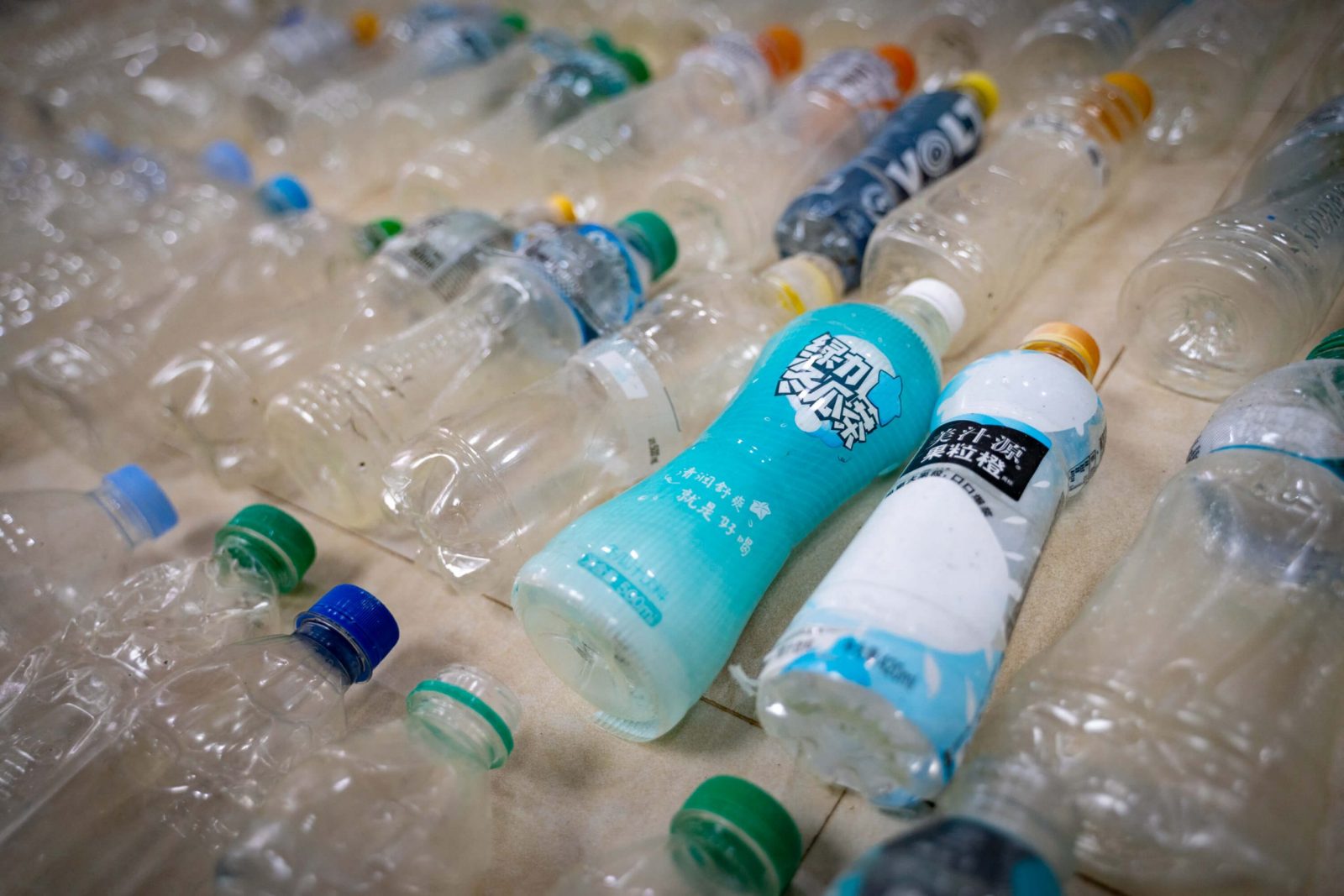 A blue water bottle with a Chinese label lays amongst a bunch of other plastic bottles